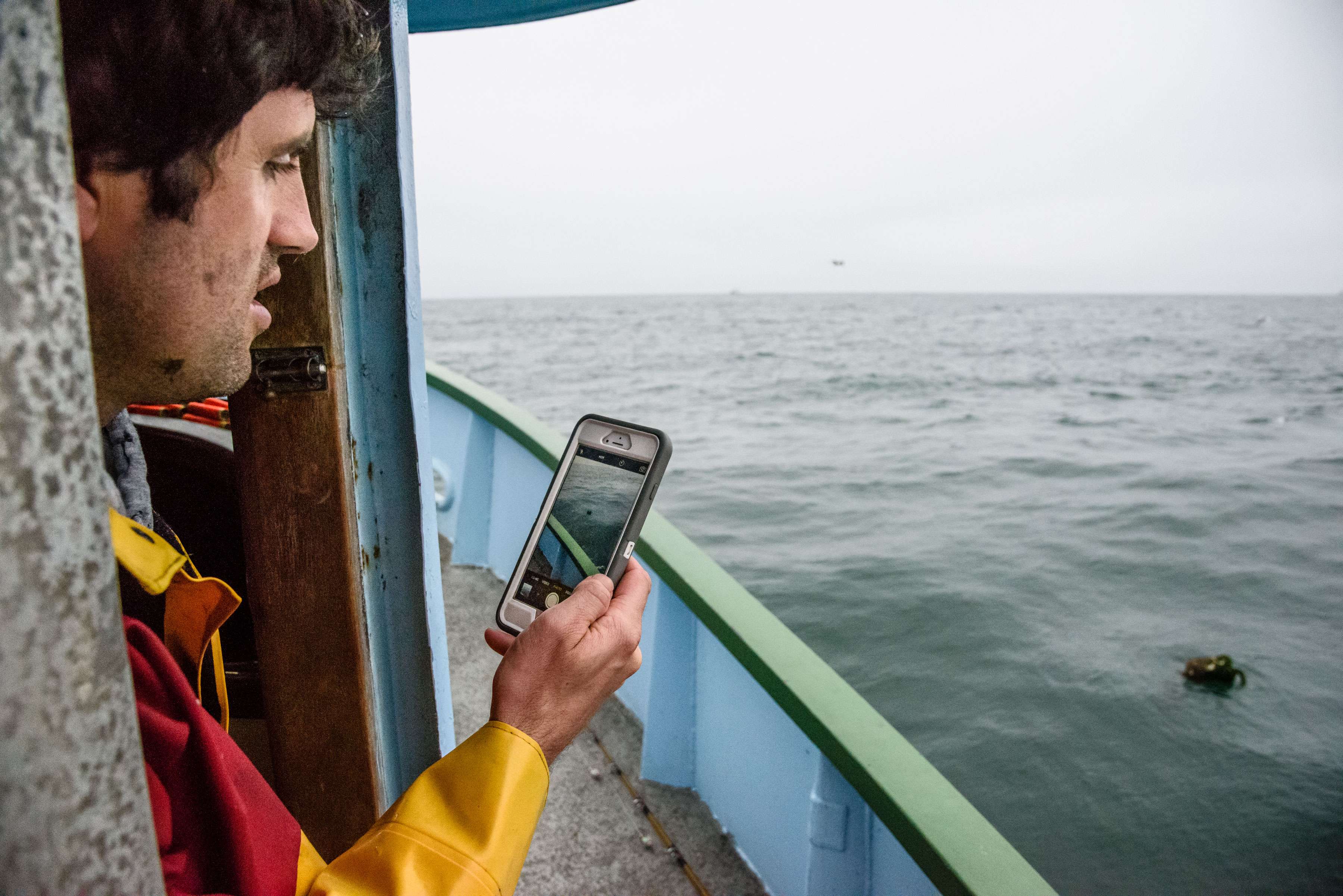 A crab fisher looks at his phone to track lost gear. 