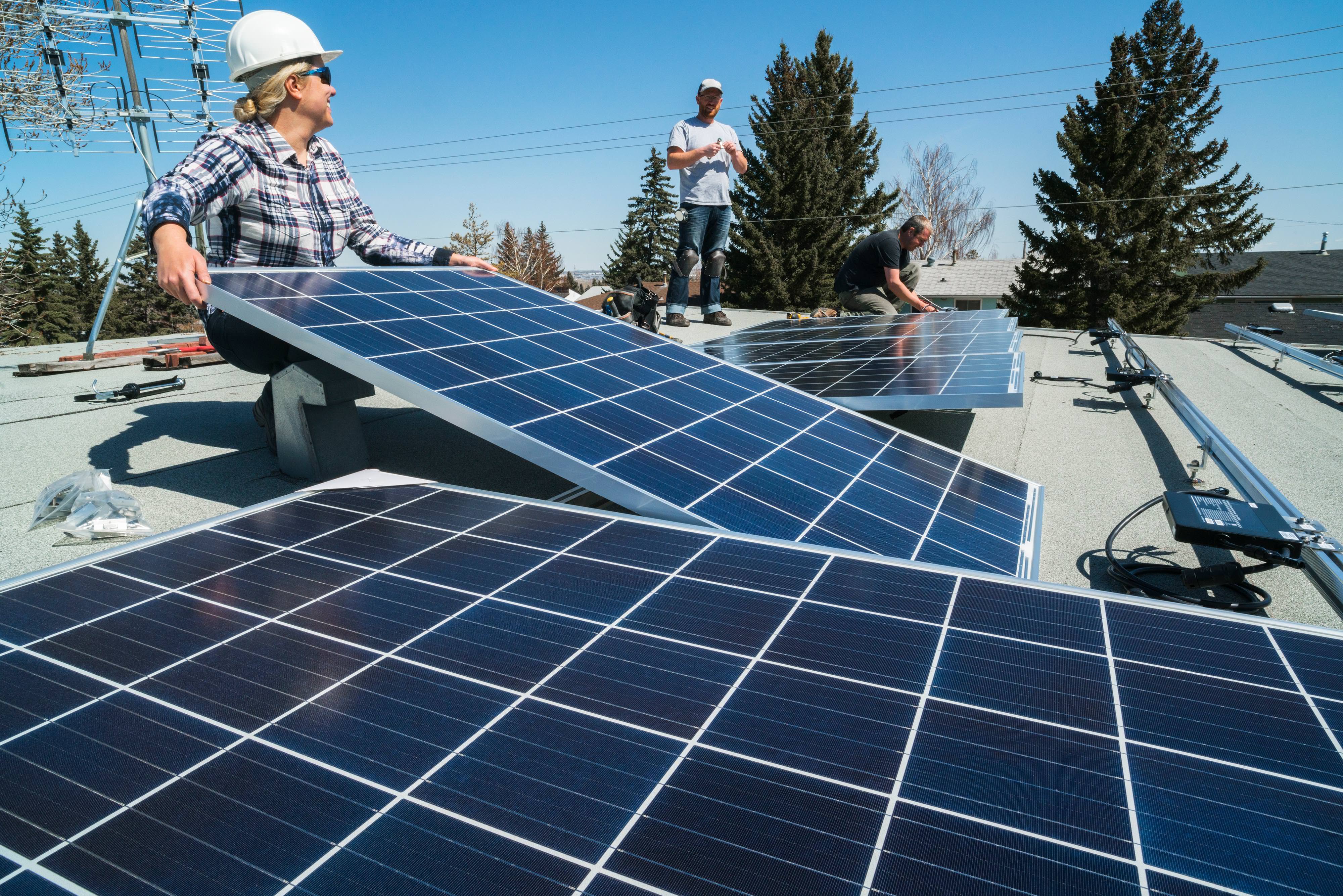 Workers install solar panels on roof.