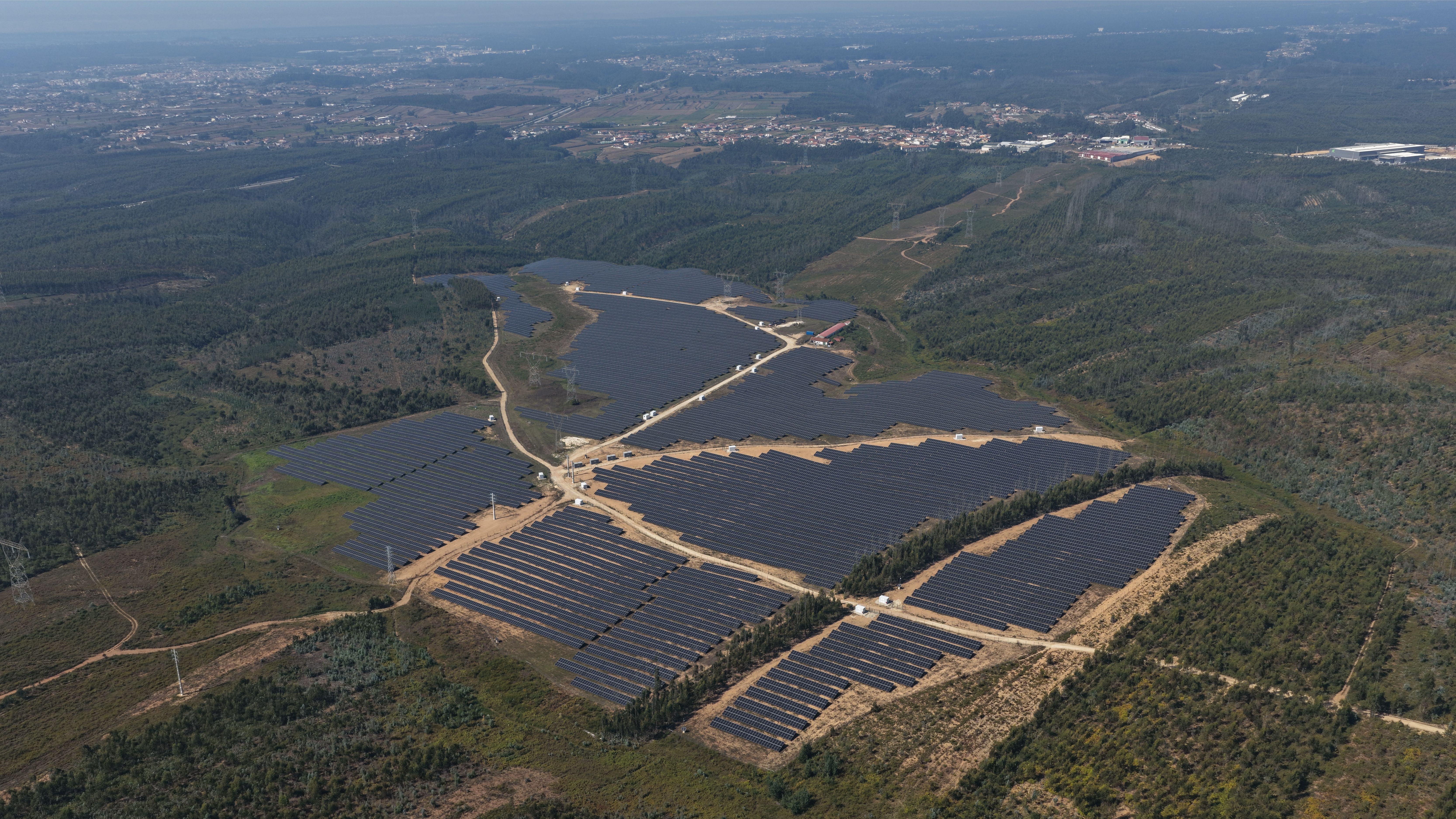 Aerial view of a solar farm in a forested landscape.