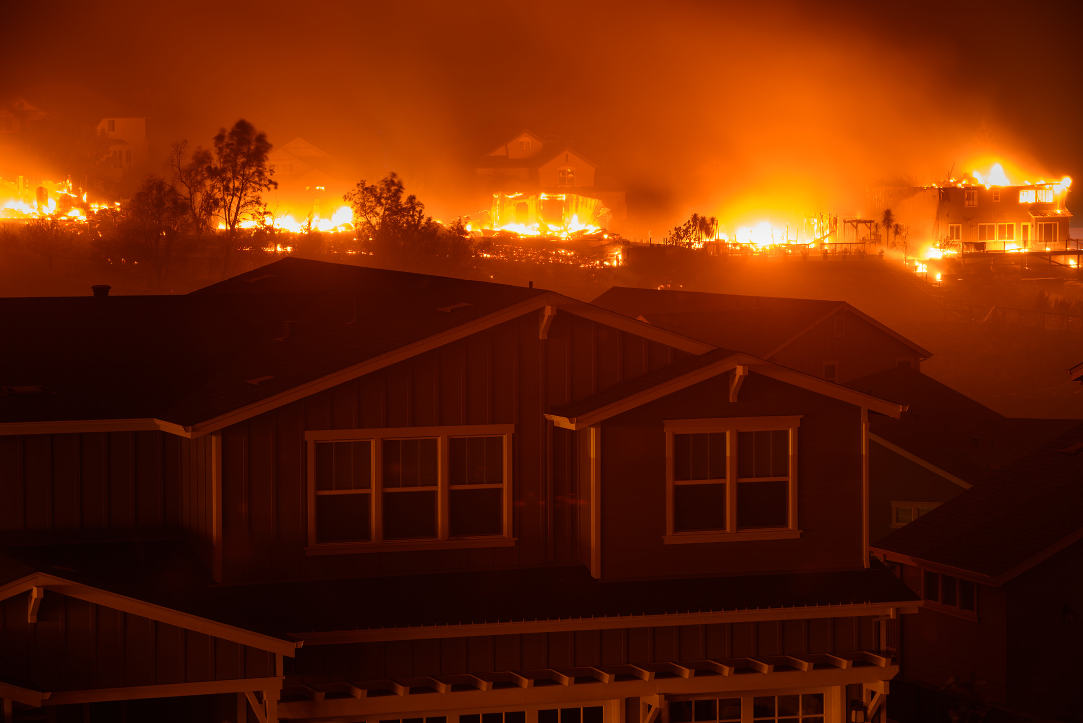 A house with a fire raging in the background.