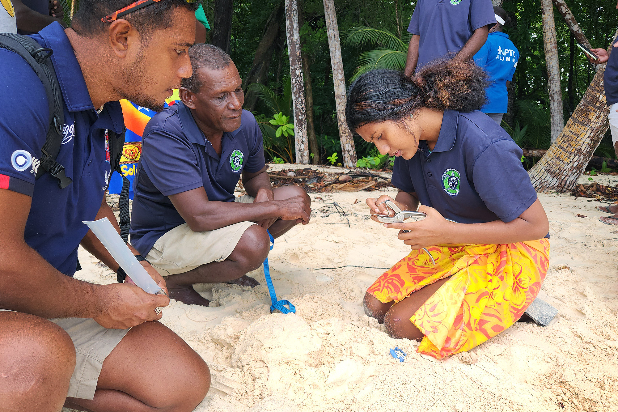 A group of people kneeling in the sand.