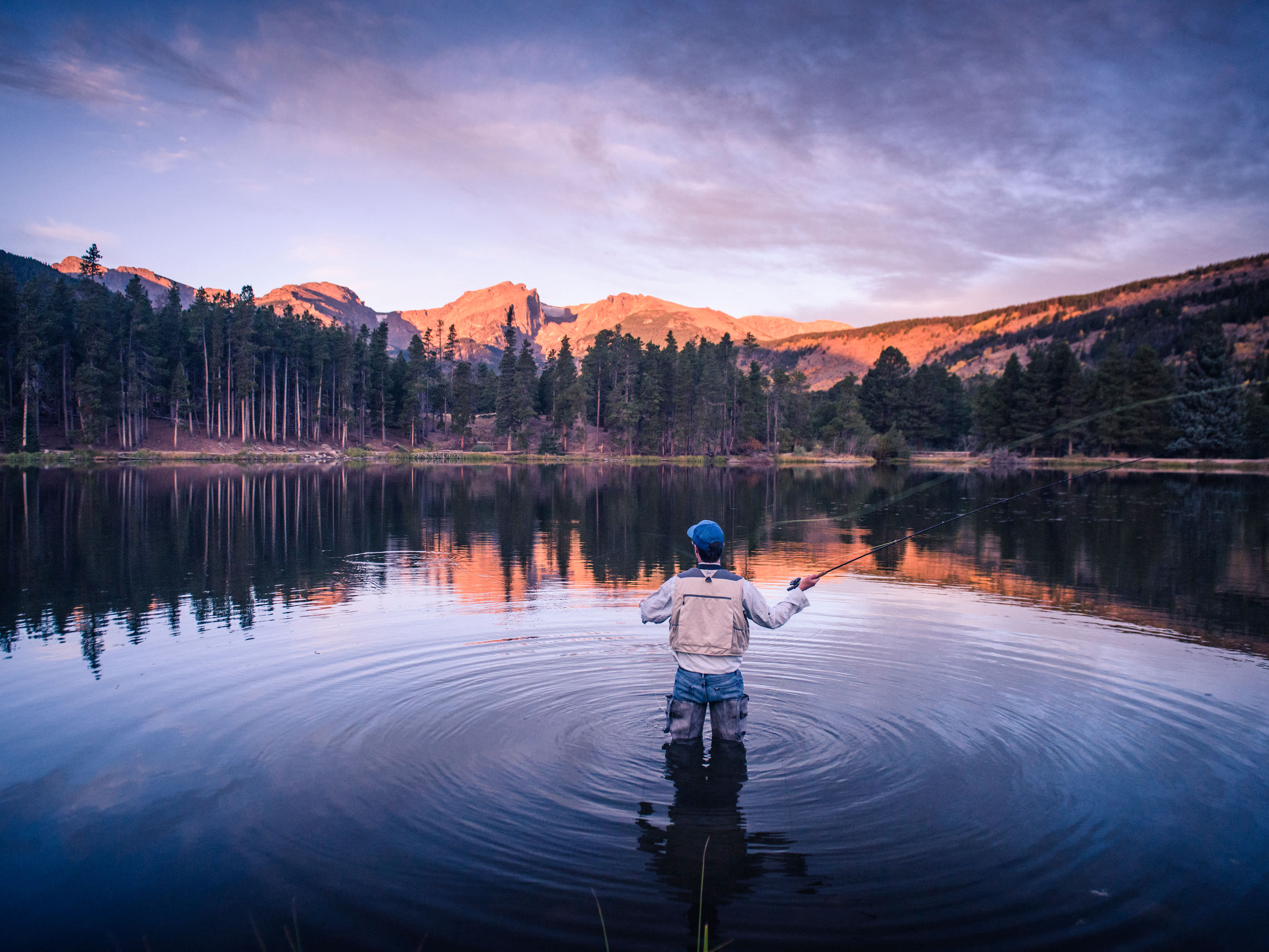 A person standing in a lake fly fishing.