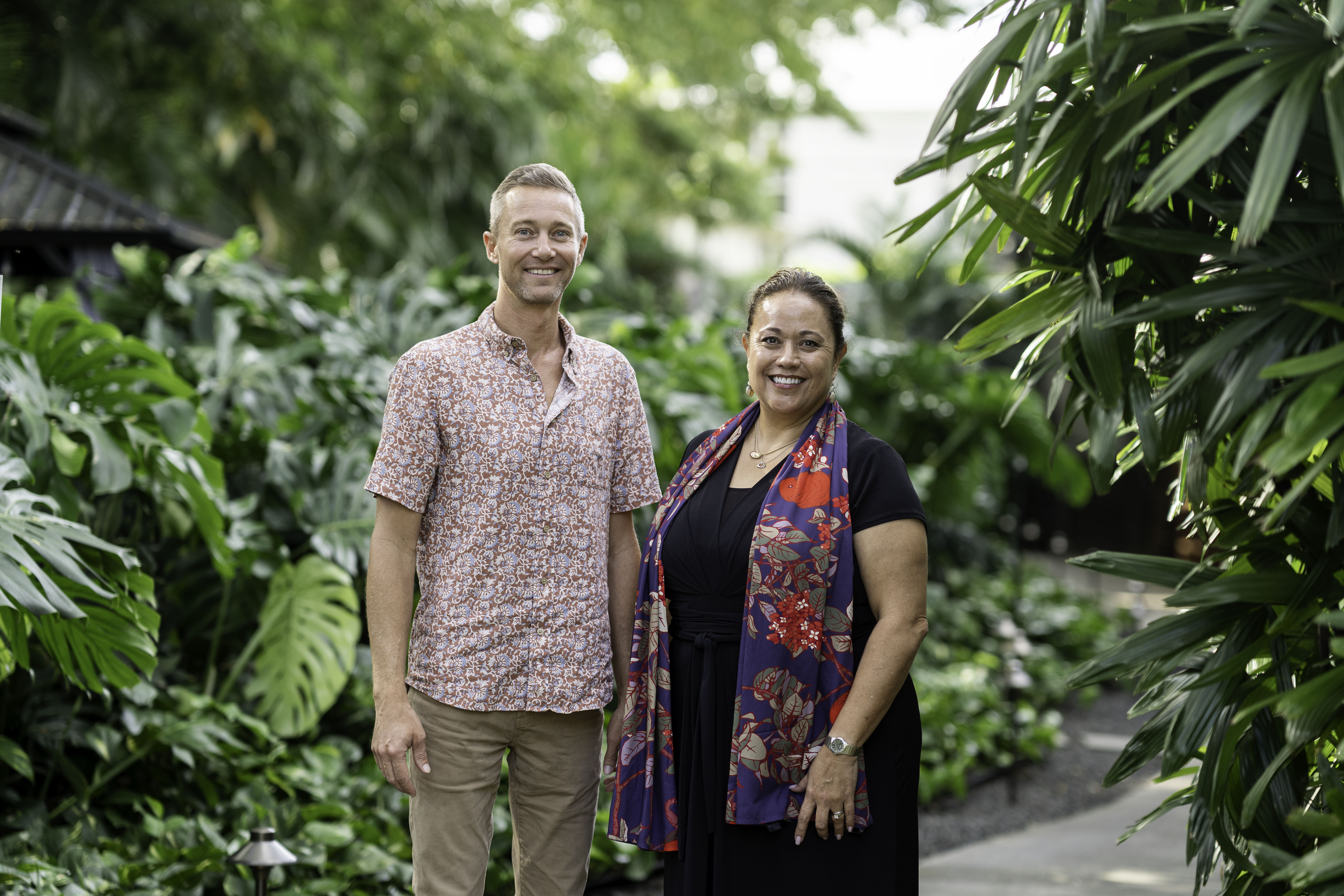 Ulalia Woodside Lee, Executive Director, and Brett MacNaughton, Board Chair, stand together in a forest.