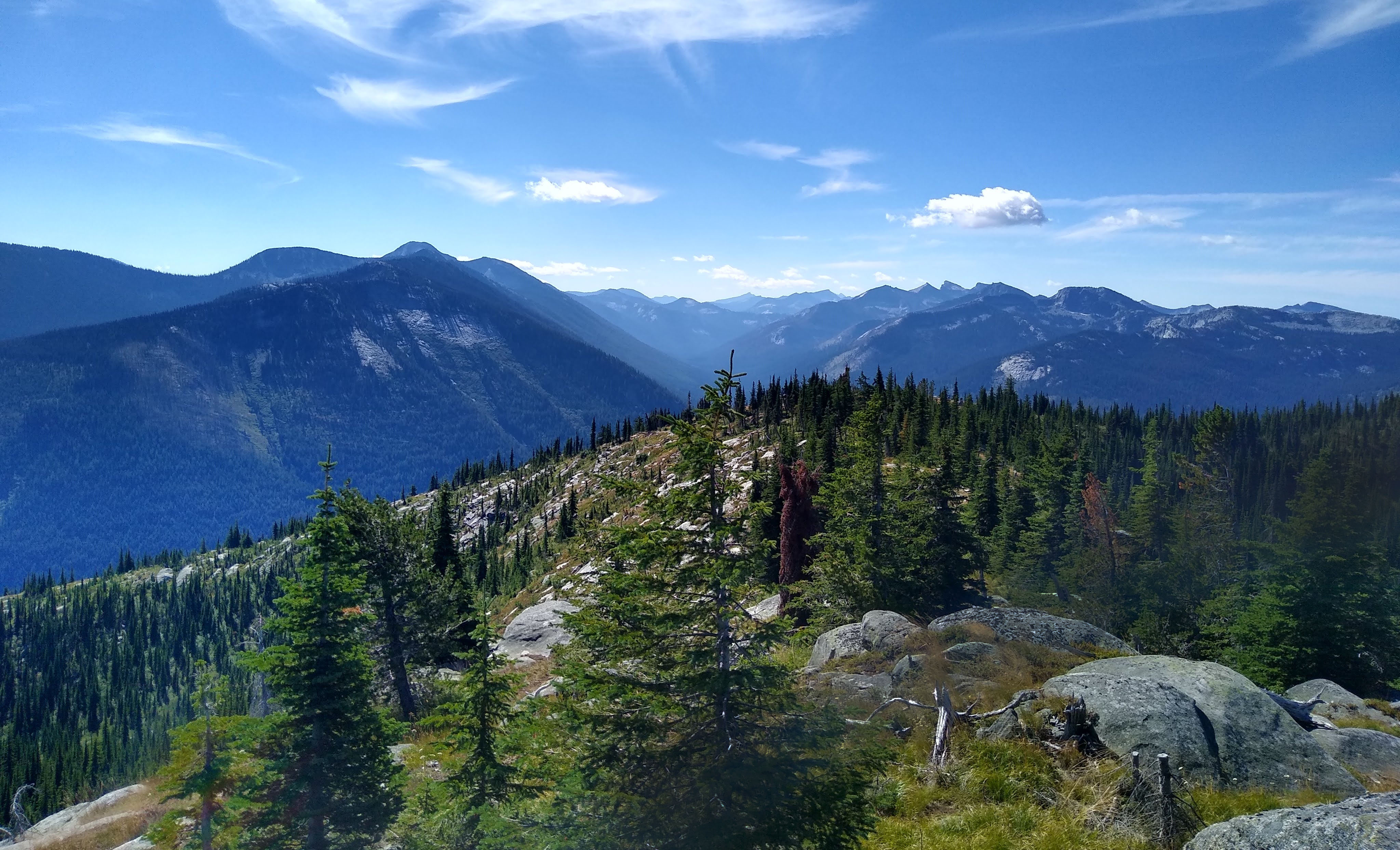 Some clouds in the sky frame a forested mountain landscape.