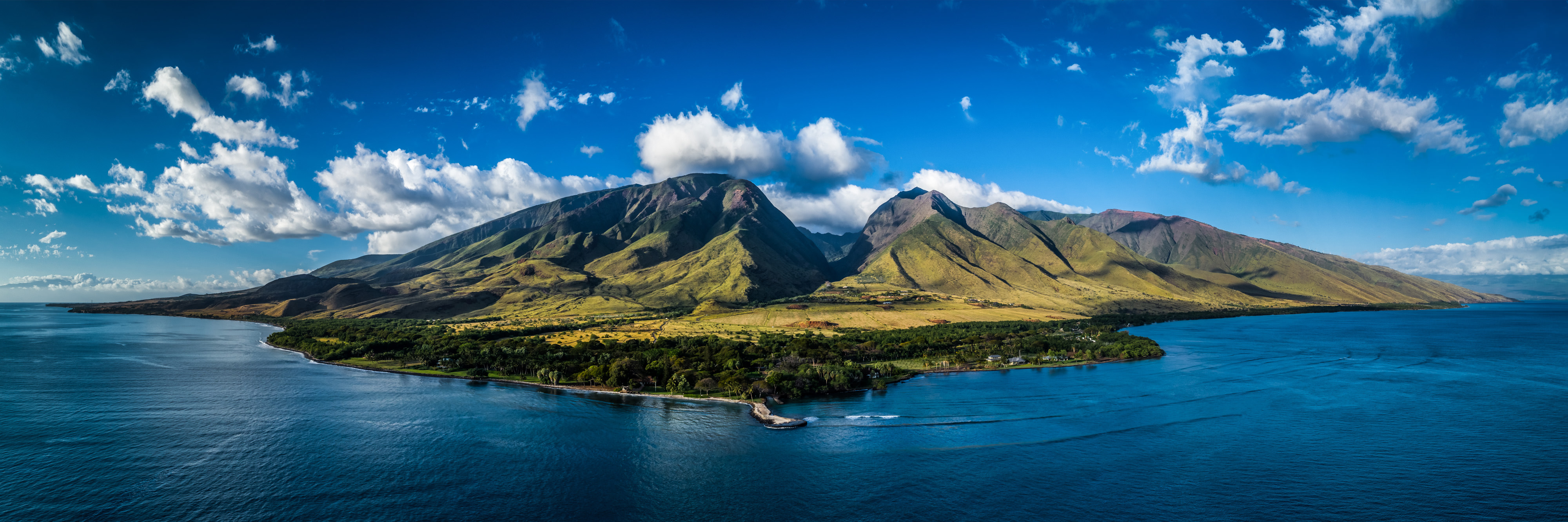 A mountain emerges from dark blue waters of the sea.