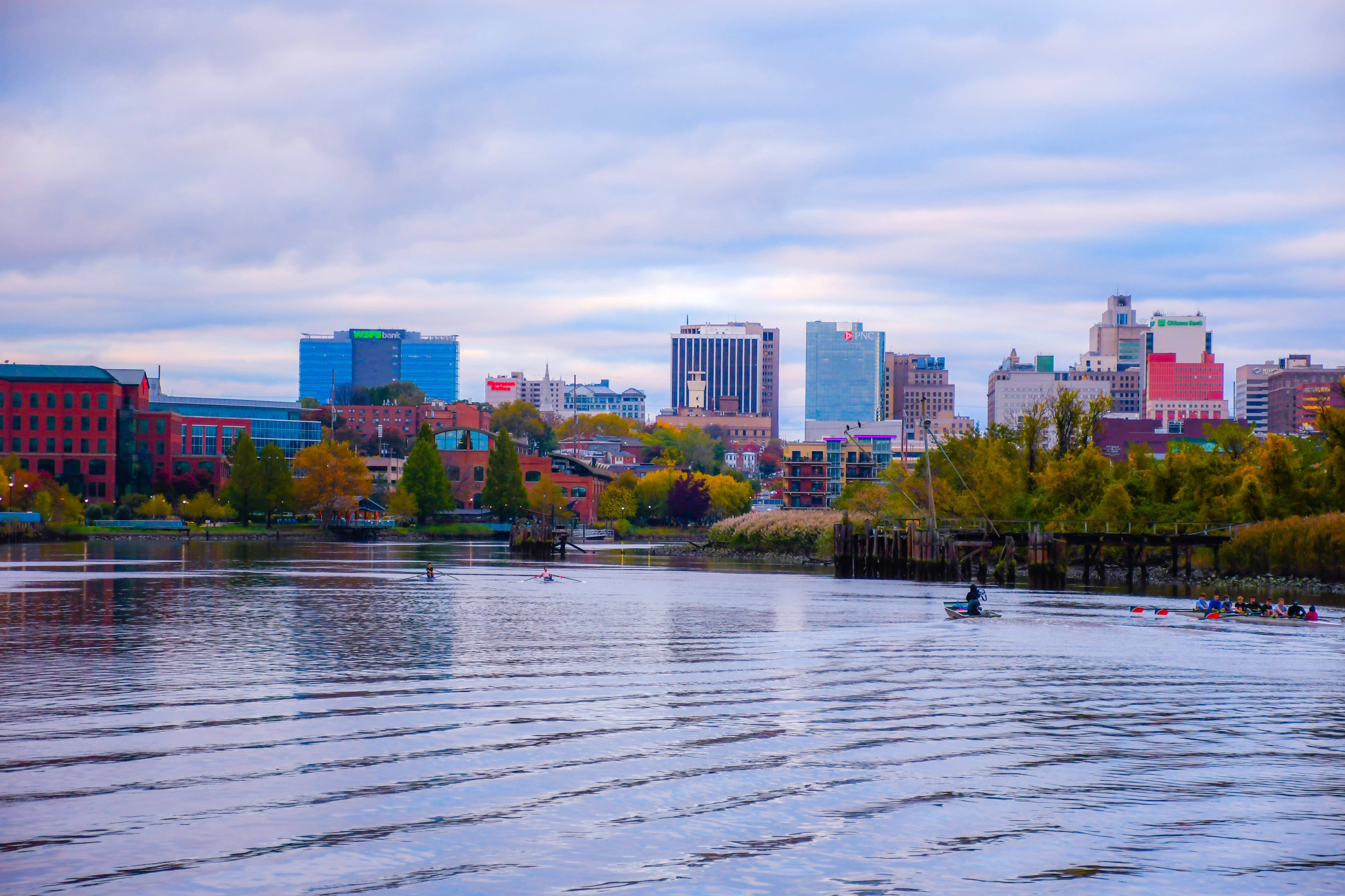 A river calmly flows toward a city skyline.