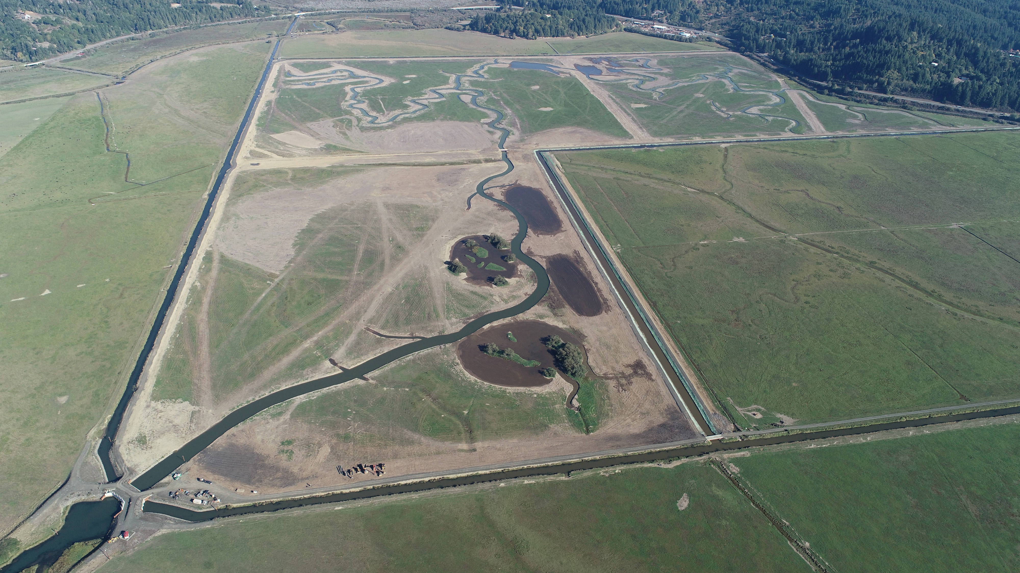 Aerial view of a relatively flat plain with canals and rivers cutting across it and a few round and oval lakes alongside the rivers.