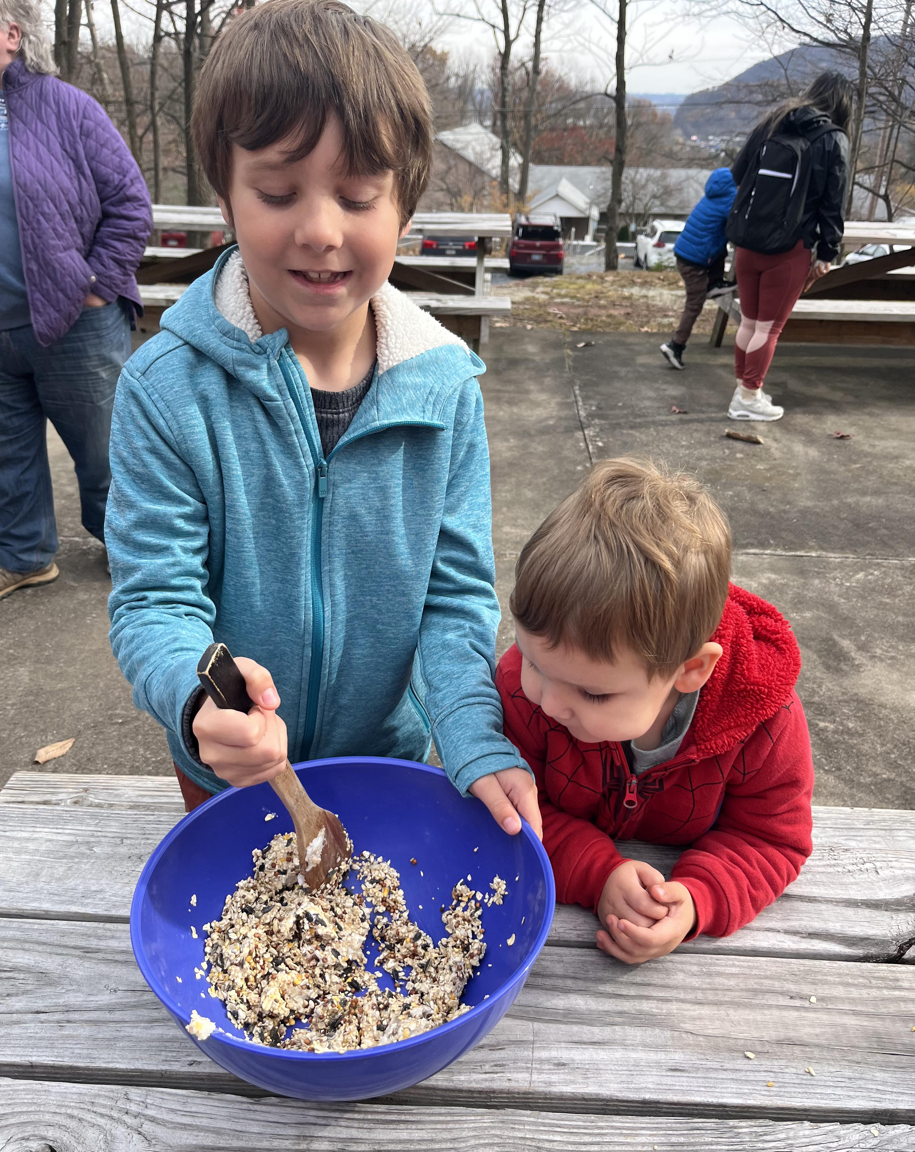 Two young volunteers mixing up bird food in a bowl.