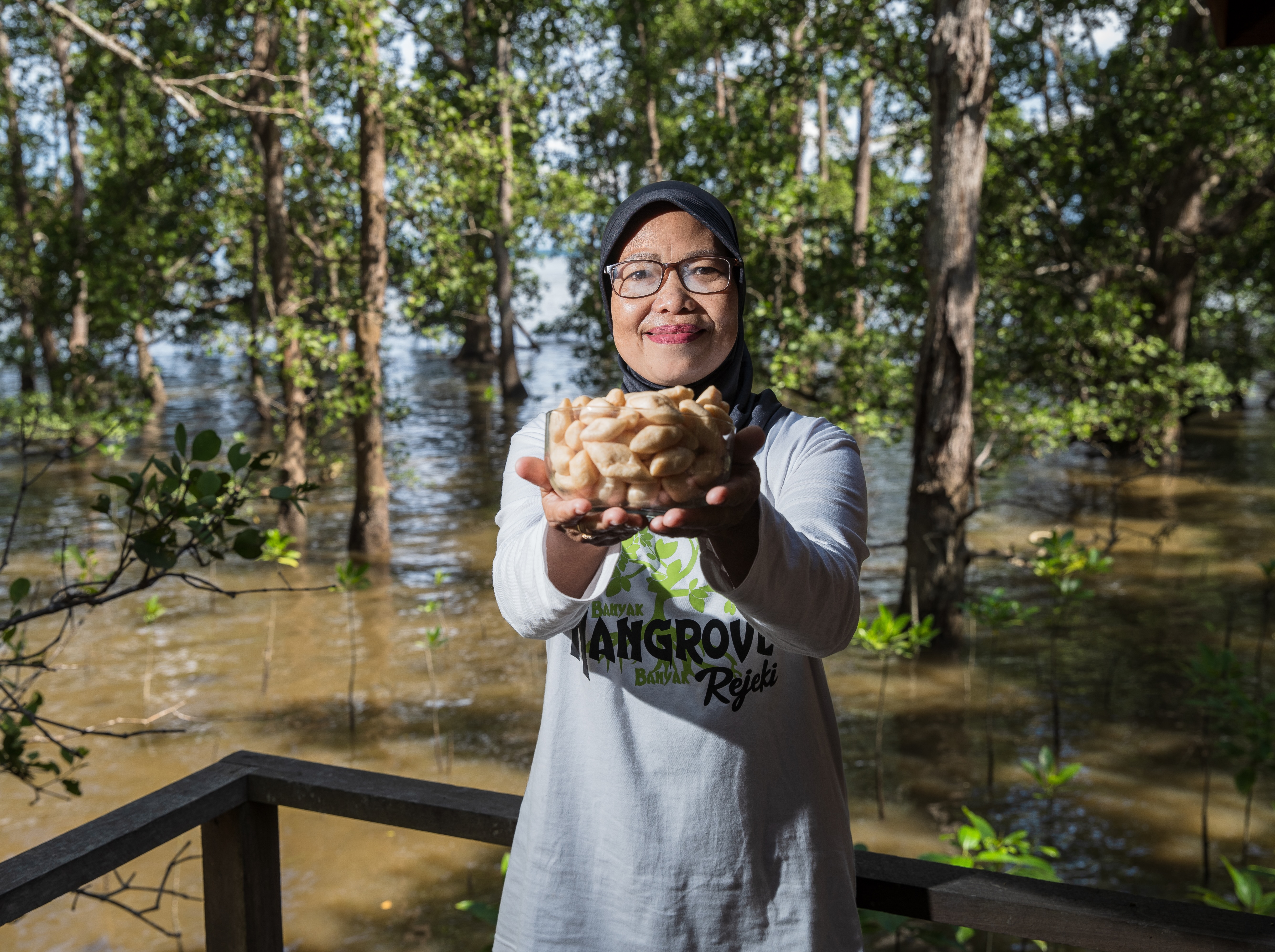 a woman holding a handful of shrimp up to the camera.
