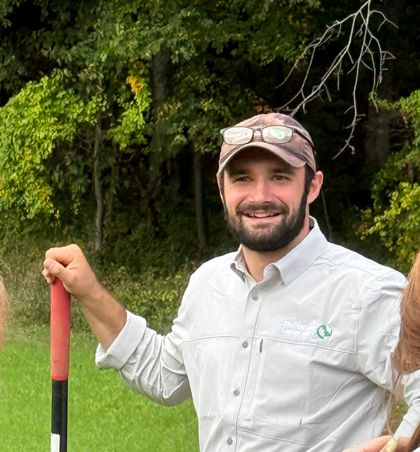 A man wearing a hat and Nature Conservancy shirt poses for a photo.