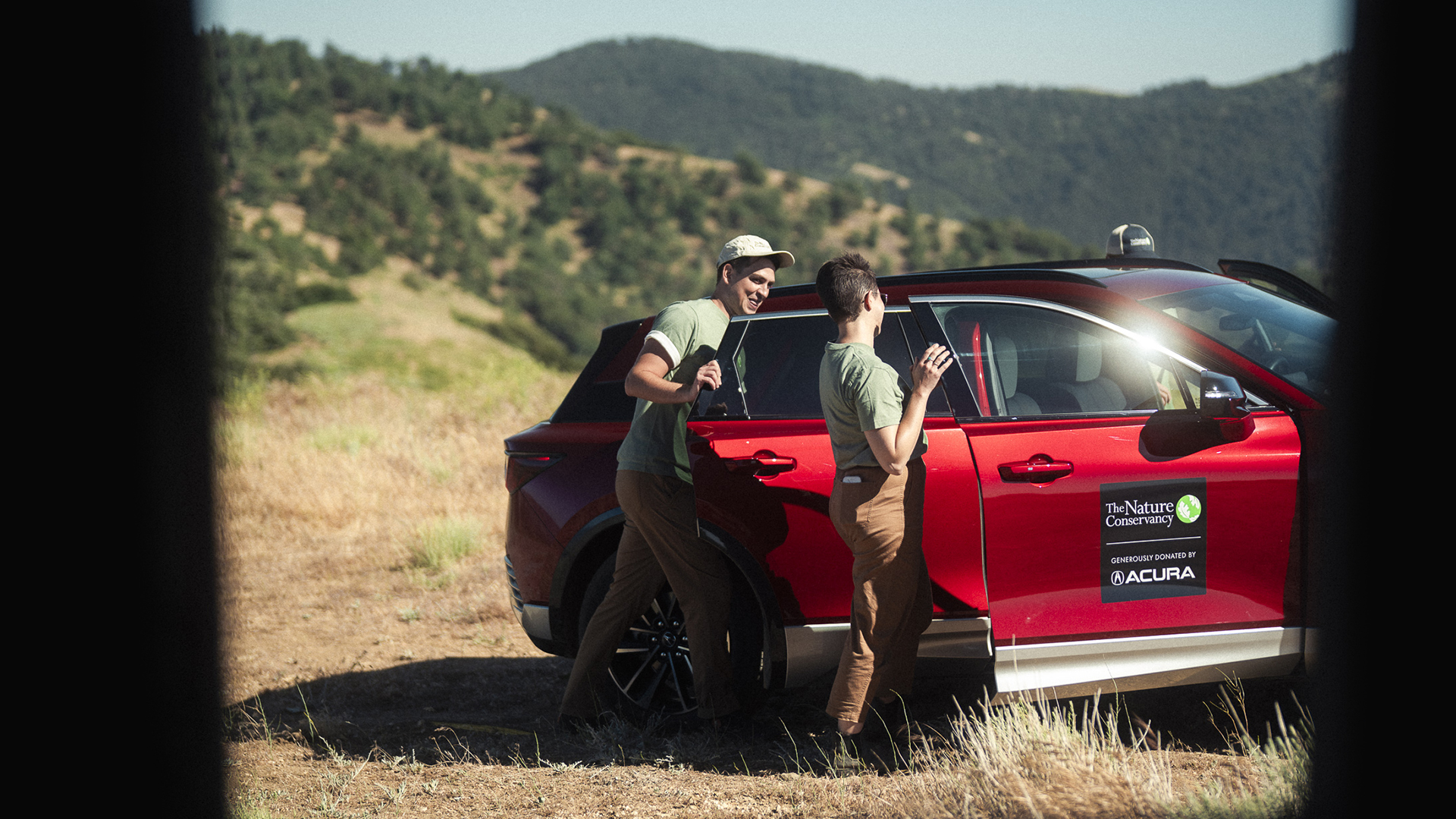 Two TNC employee get out of an electric SUV on a hill.