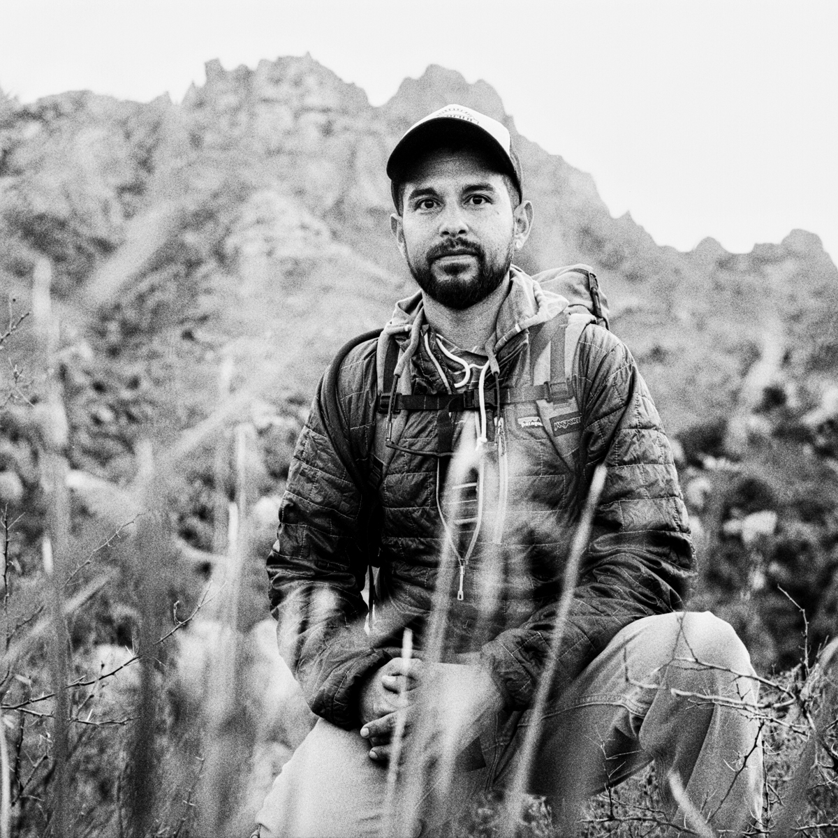 black & white photo of man with goatee kneeling.